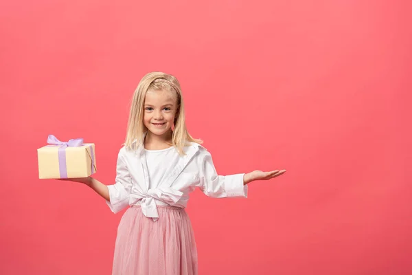 Lindo Sonriente Niño Con Mano Extendida Sosteniendo Regalo Aislado Rosa — Foto de Stock