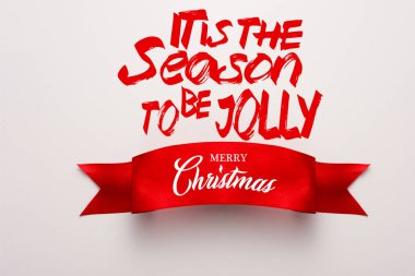 Kırmızı kurdelenin en üst görüntüsü, beyaz üzerine neşeli, mutlu noel yazıları yazma mevsimi. 