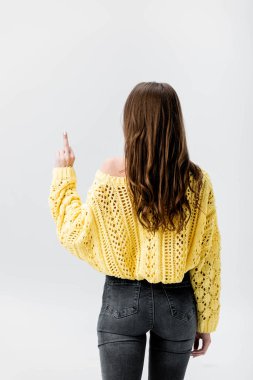 back view of girl in yellow sweater showing middle finger isolated on grey clipart