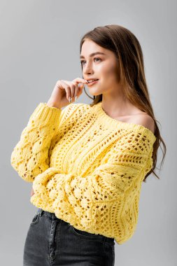 Gri renge bakarken dudaklarına dokunan cilveli genç bir kadın.