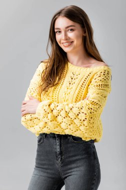 attractive girl in yellow sweater smiling at camera isolated on grey clipart