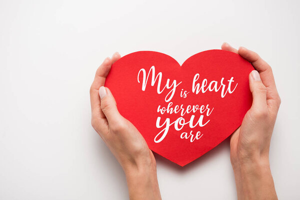 cropped view of woman holding red heart shape paper cut with my heart is wherever you are letters on white 