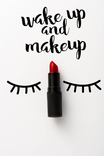 top view of black tube with red lipstick near wake up and makeup letters on white 