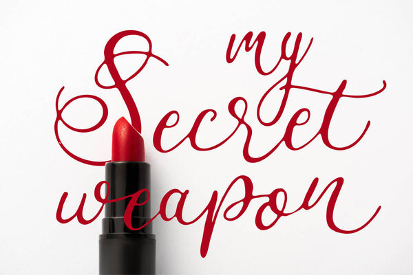 top view of black tube with red lipstick near my secret weapon letters on white 