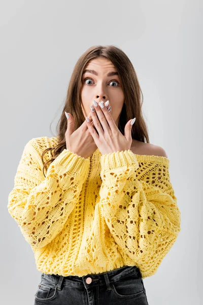 surprised girl covering mouth with hands while looking at camera isolated on grey