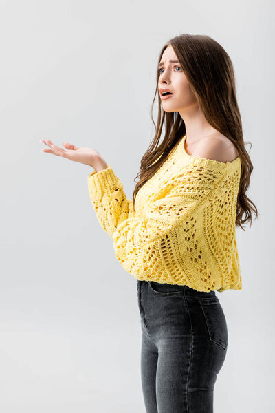 обескураженная девушка показывает негодование жест, глядя в сторону изолированы на серый
