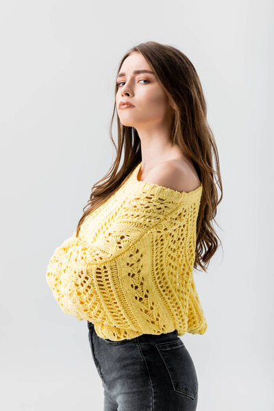 dissatisfied girl standing with crossed arms and looking at camera isolated on grey