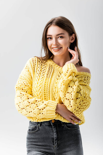 счастливая девушка смотрит в камеру, прикасаясь к лицу, изолированному от серого
