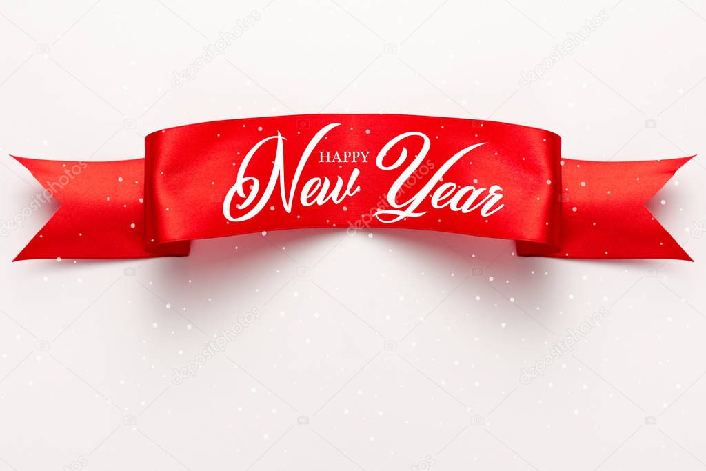 top view of red satin ribbon with happy new year lettering on white 