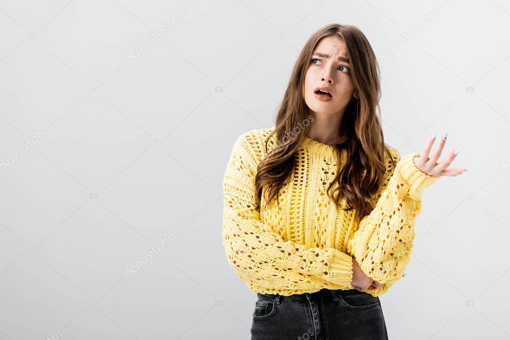 disappointed girl showing indignation gesture while looking away isolated on grey