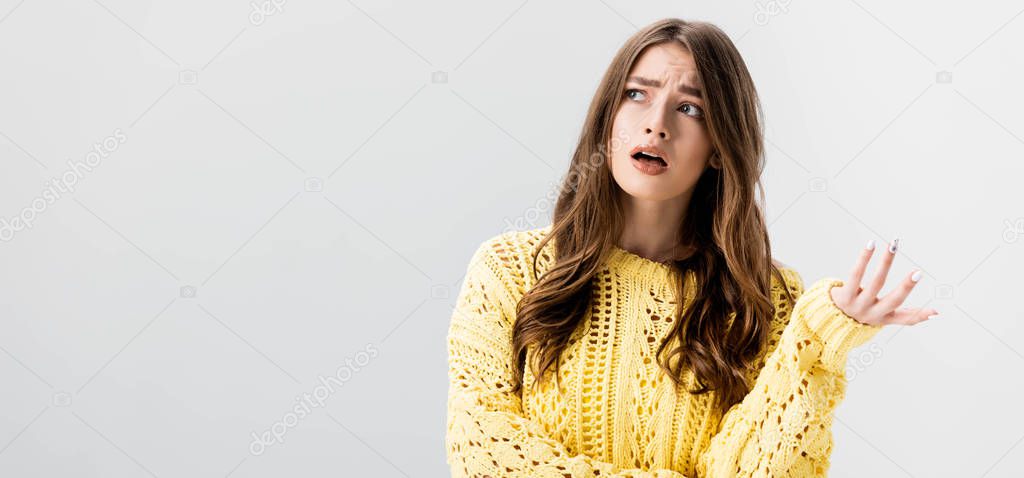panoramic shot of dissatisfied girl showing indignation gesture while looking away isolated on grey
