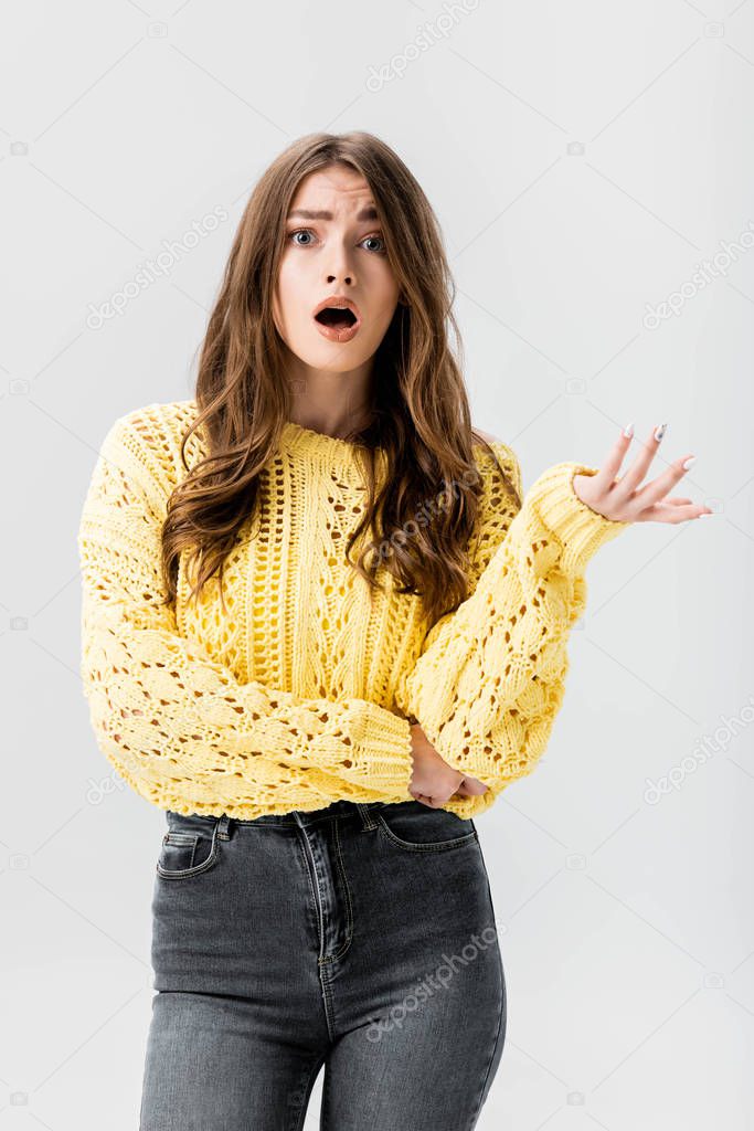 dissatisfied girl showing indignation gesture while looking at camera isolated on grey