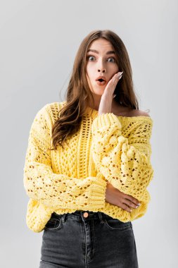 Şok olmuş kadın yüzüne dokunuyor ve gri renkli kameraya bakıyor.