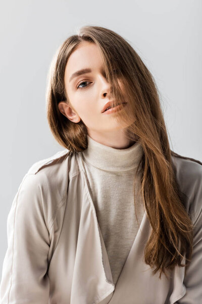 attractive, confident young woman looking at camera isolated on grey