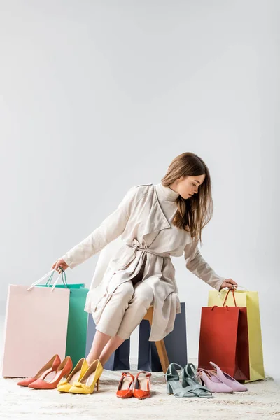Modna Młoda Kobieta Trzyma Torby Zakupy Siedząc Obok Kolekcji Butów — Zdjęcie stockowe