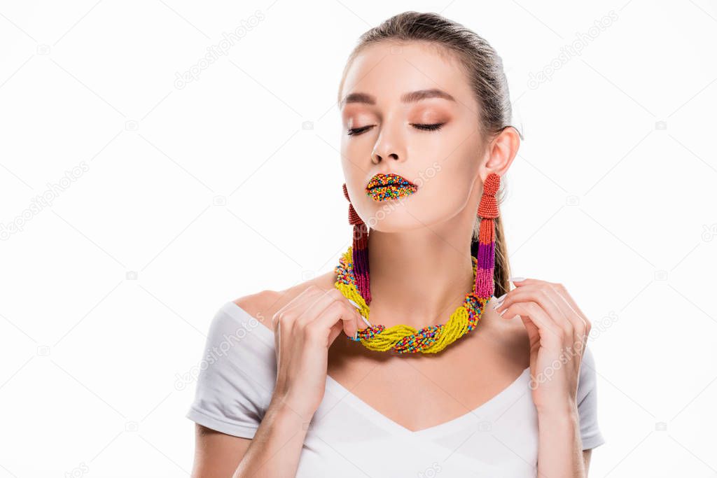 beautiful girl in beaded accessories, with beads on lips, touching necklace isolated on white
