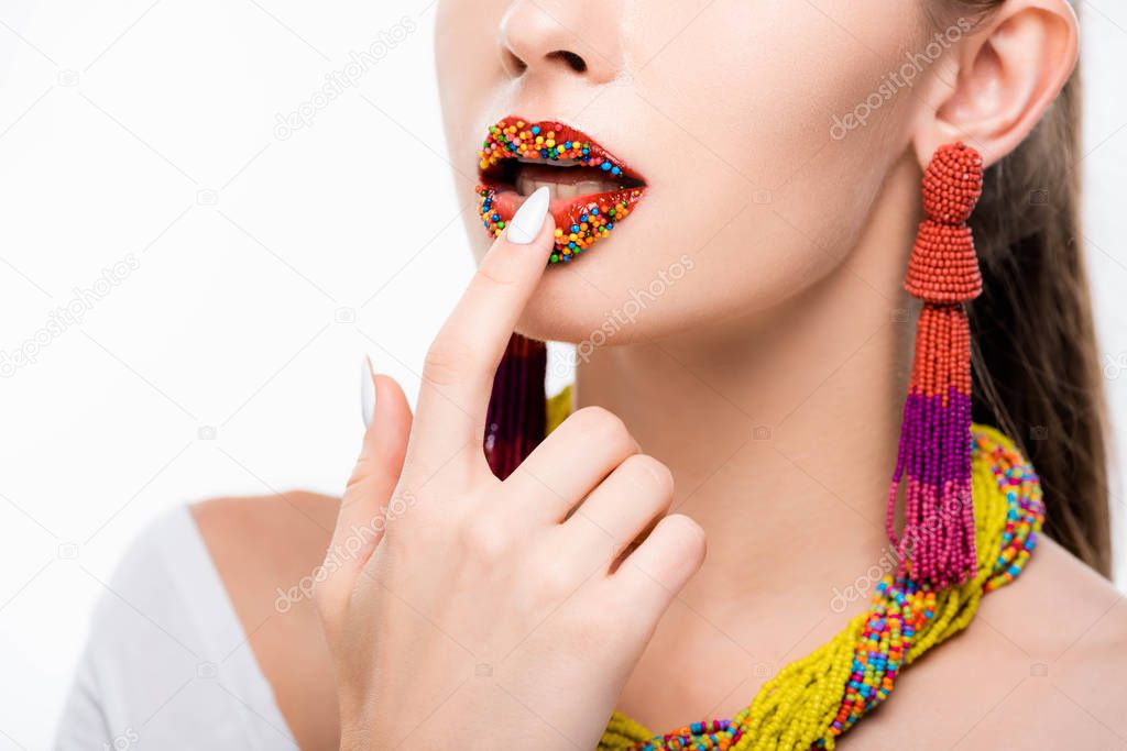 partial view of girl in beaded necklace and earrings touching beads on lips isolated on white