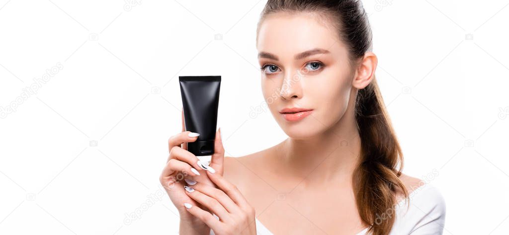 panoramic shot of beautiful girl looking at camera while holding tube with hand cream isolated on white