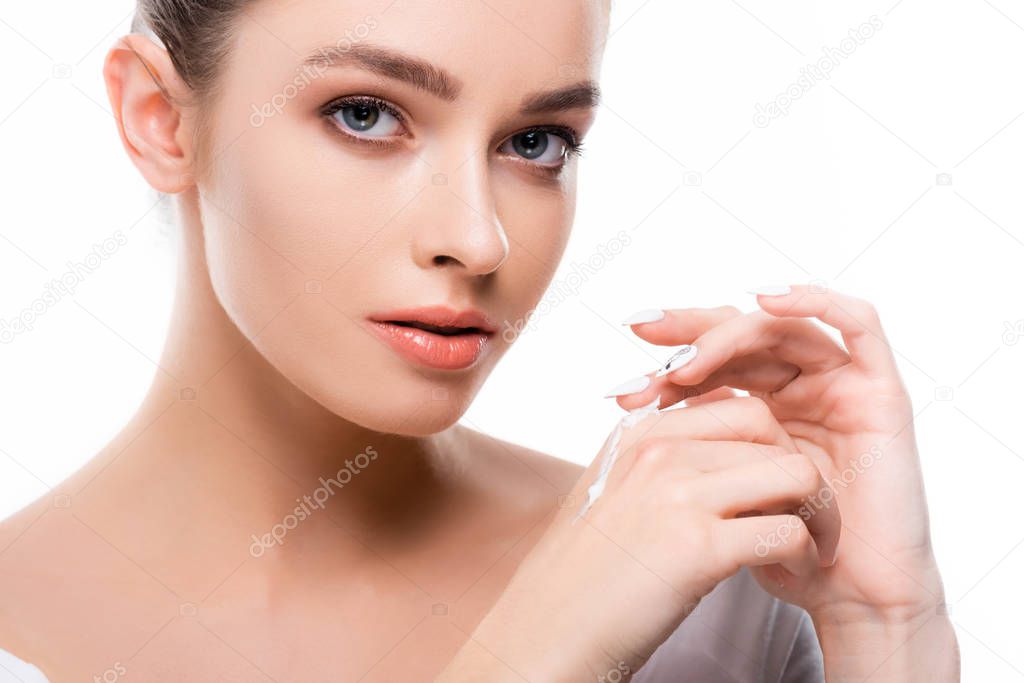 beautiful young woman applying hand cream and looking at camera isolated on white