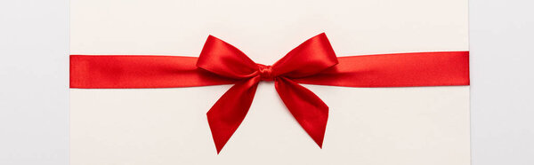 panoramic shot of red satin bow on envelope isolated on white 