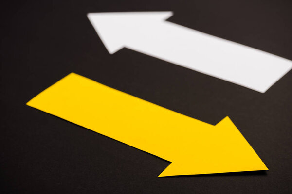 selective focus of yellow directional arrow isolated on black 