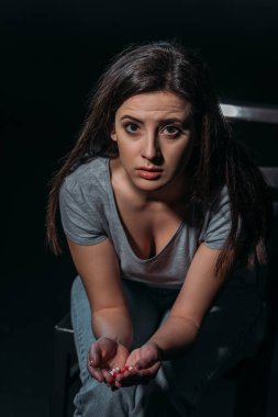 Depresyonda olan bir kadın elinde bir avuç hapla kameraya bakıyor ve siyah üzerine izole bir şekilde intihar ediyor.