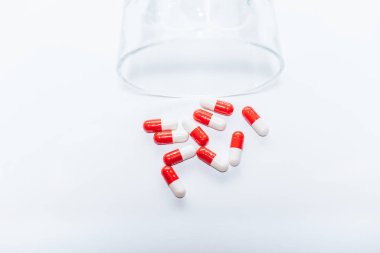 red and white capsules near overturned glass on white background, suicide prevention concept clipart