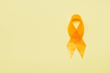 top view of yellow awareness ribbon on yellow background, suicide prevention concept clipart