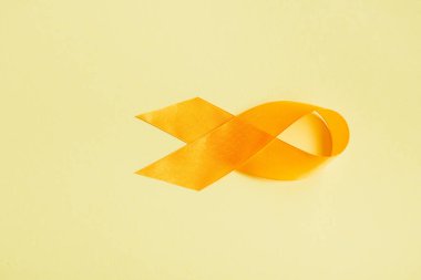 top view of yellow awareness ribbon on yellow background, suicide prevention concept clipart