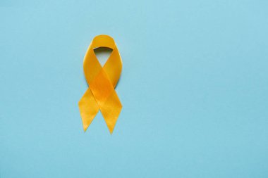 top view of yellow awareness ribbon on blue background, suicide prevention concept clipart