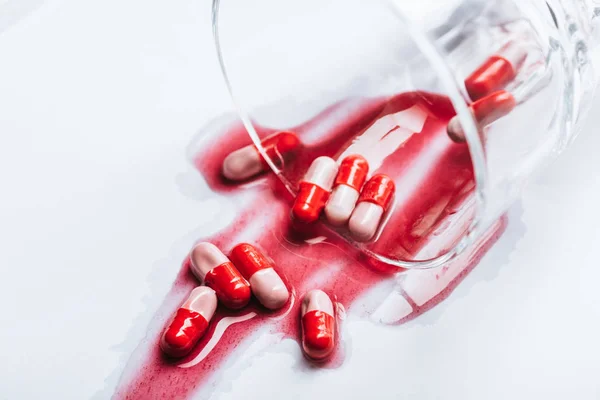 Ανατρεπόμενο Γυαλί Και Υγρά Χάπια Κόκκινες Διαρροές Νερού Λευκό Φόντο — Φωτογραφία Αρχείου