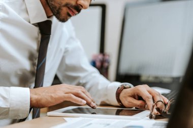 Masada oturan ve dijital tablet kullanan iki ırklı tüccarın kırpılmış görüntüsü 