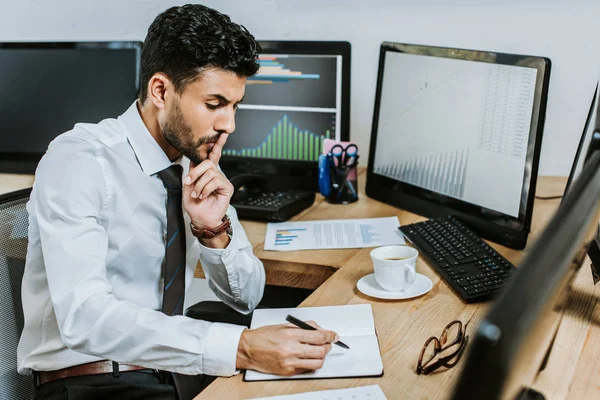 Pensive Raciale Handelaar Schrijven Notebook Zitten Aan Tafel — Stockfoto