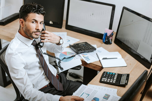 high angle view of bi-racial trader talking on telephone 