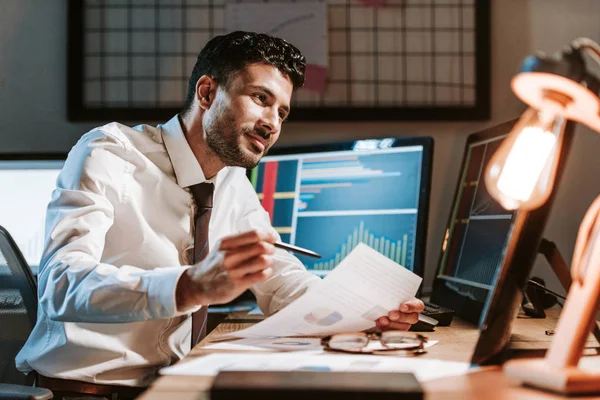 Sonriente Racial Comerciante Celebración Papel Mirando Computadora Con Gráficos — Foto de Stock