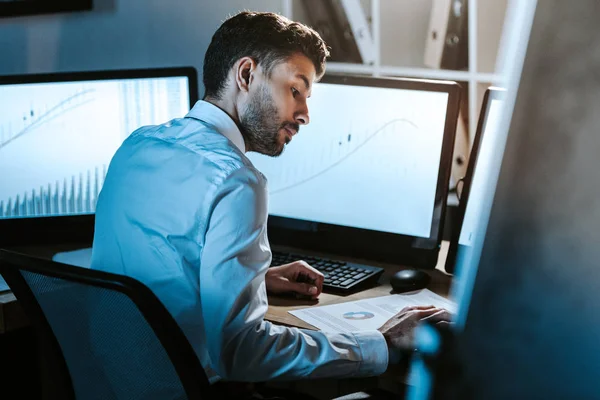 Comerciante Racial Mirando Papel Sentado Cerca Las Computadoras Con Gráficos — Foto de Stock