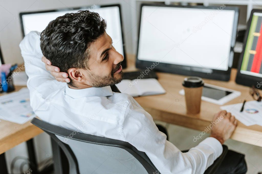 selective focus of smiling bi-racial trader looking away in office 