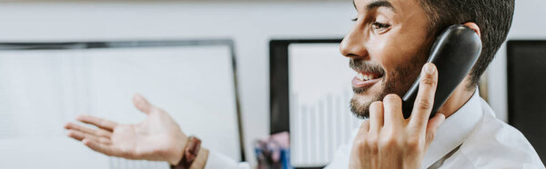 панорамный снимок улыбающегося двурасового торговца, разговаривающего по телефону
 