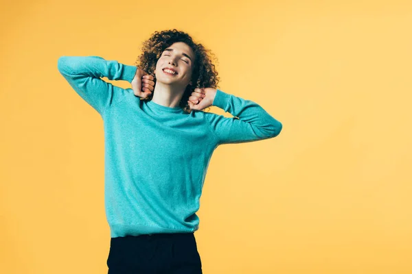 Smiling Curly Teenager Stretching Himself Closed Eyes Isolated Yellow — Stock Photo, Image