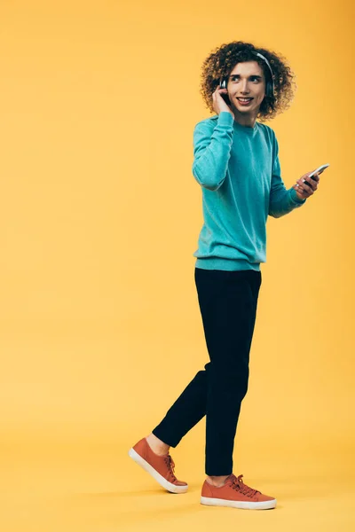 Sorrindo Encaracolado Adolescente Segurando Smartphone Ouvir Música Fones Ouvido Enquanto — Fotografia de Stock