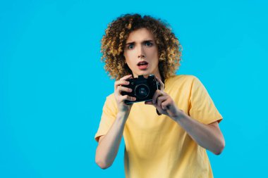 Şok olmuş kıvırcık ergen, mavi kameraya izole edilmiş bir şekilde fotoğraf çekiyor.