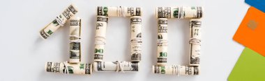 panoramic shot of one hundred dollar banknotes in cash rolls on white  clipart