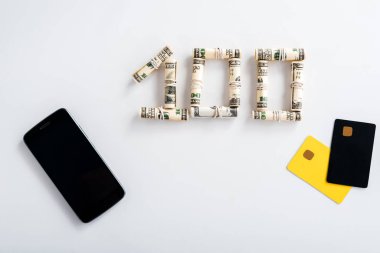 top view of smartphone with blank screen near cash rolls and credit card templates on white  clipart