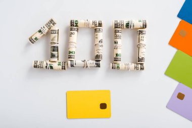 100 dolarlık banknotların en üst görüntüsü beyaz kart şablonlarının yanında nakit rulo halinde. 