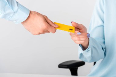 cropped view of man giving yellow credit card template to woman isolated on white  clipart