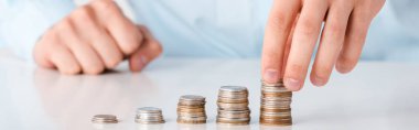 panoramic shot of man touching stack of coins isolated on white  clipart