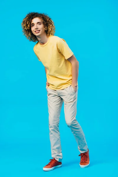 Smiling Curly Teenager Hands Pockets Isolated Blue — Stock Photo, Image
