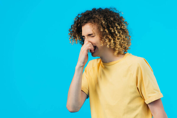 curly teenager having runny nose isolated on blue