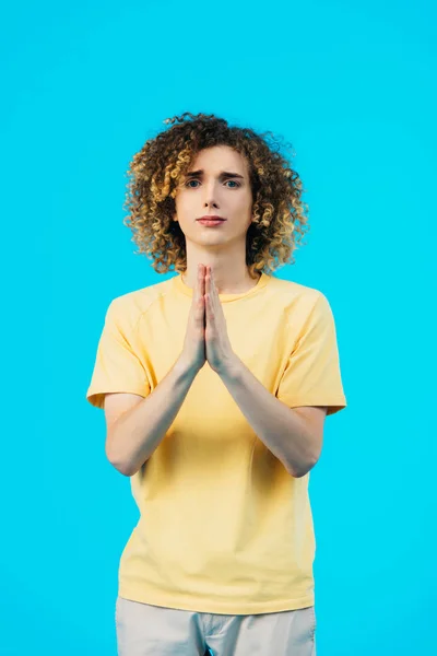 Lockiger Teenager Mit Betenden Händen Auf Blauem Grund — Stockfoto