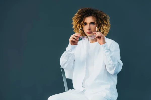 Stylish Curly Teenager Total White Outfit Putting Glasses While Sitting — Stock Photo, Image
